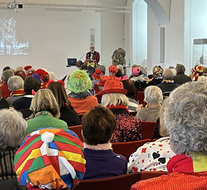 Fastnachts-KiM Maskierte Menschen hören einem Vortrag zu