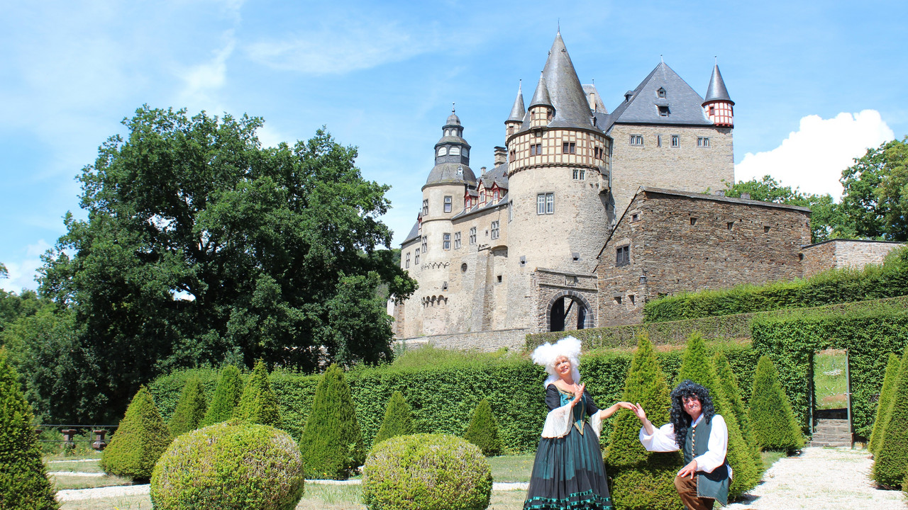 Zwei Barock kostümierte Personen vor Schloss Stolzenfels